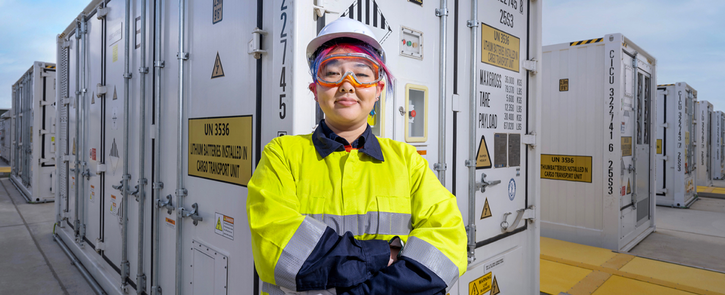 Female with protective equipment in front of shipping containers