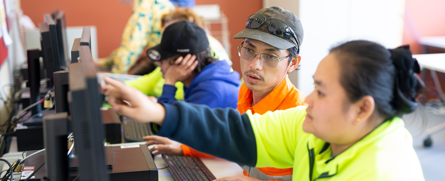 female pointing at computer with male looking