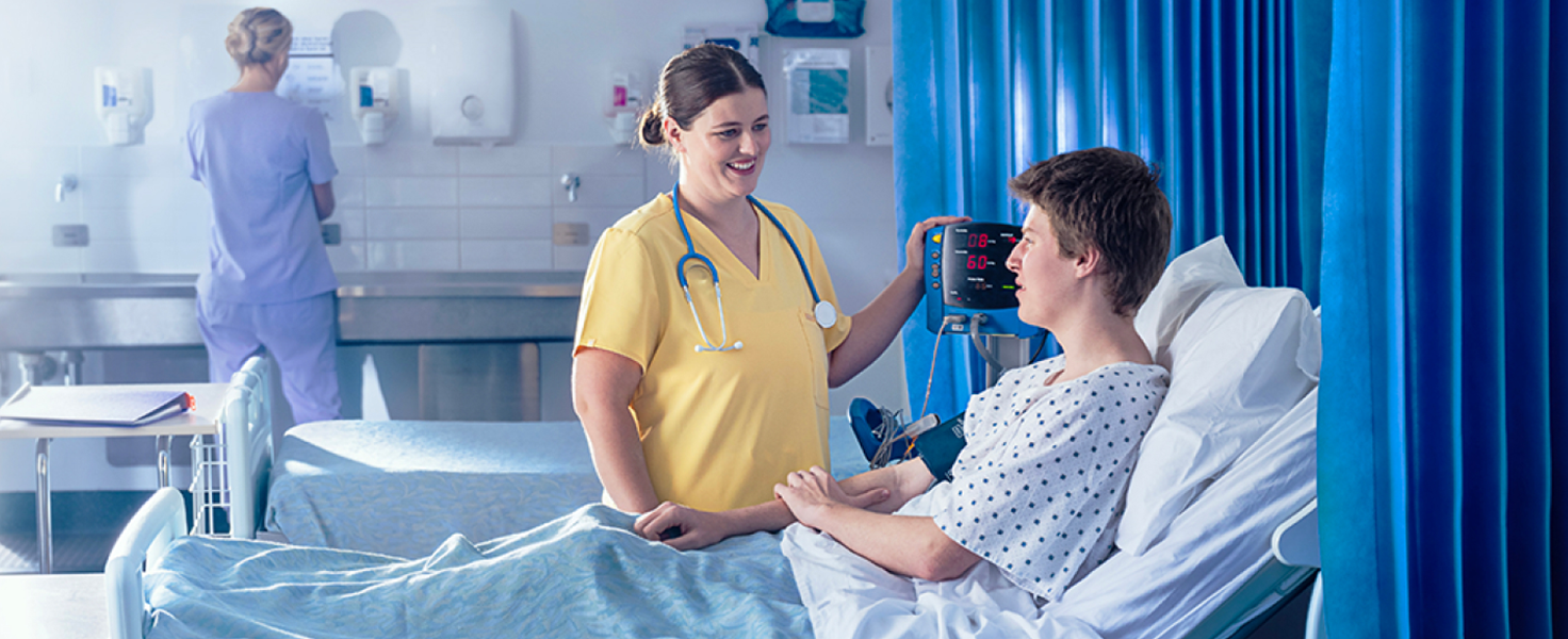 nurse with patient in a ward with another nurse in the background