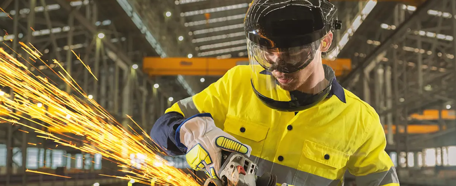 male metal fabricator with protective gear and sparks from metal works
