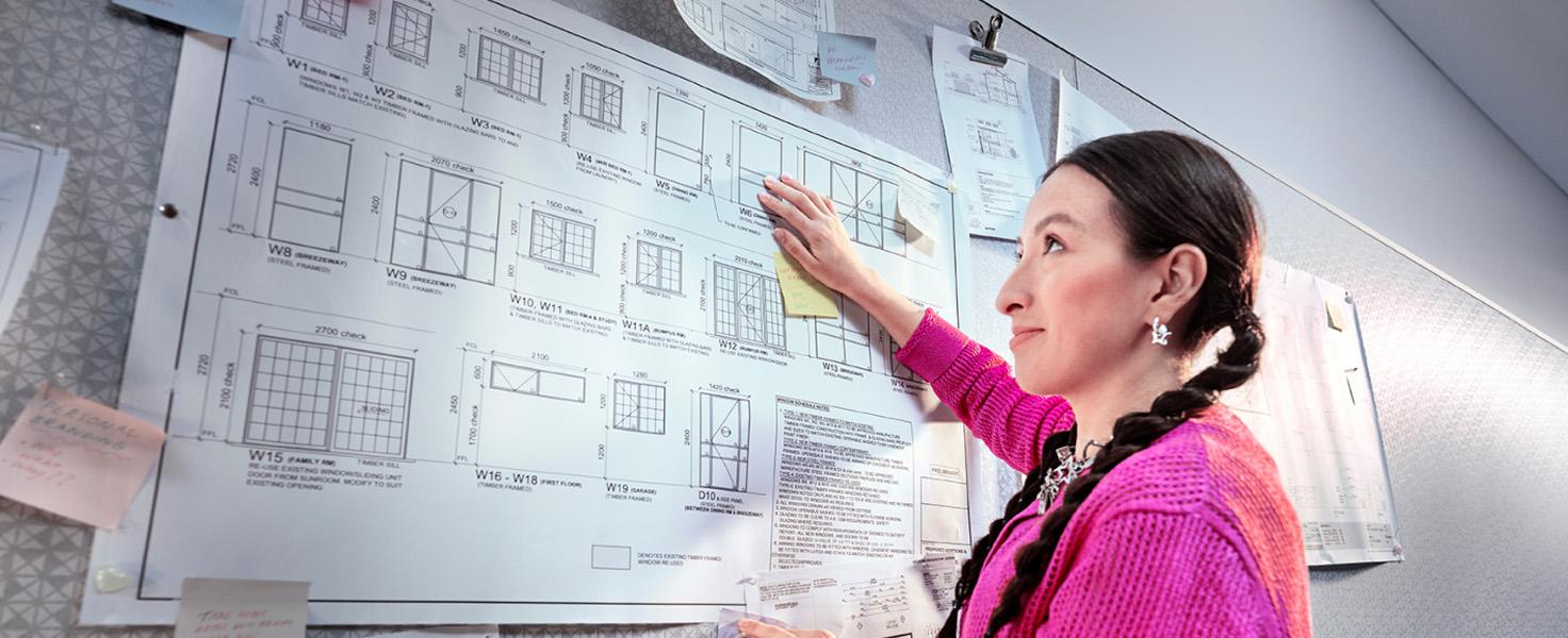 female draftsperson pointing at sketches on a board