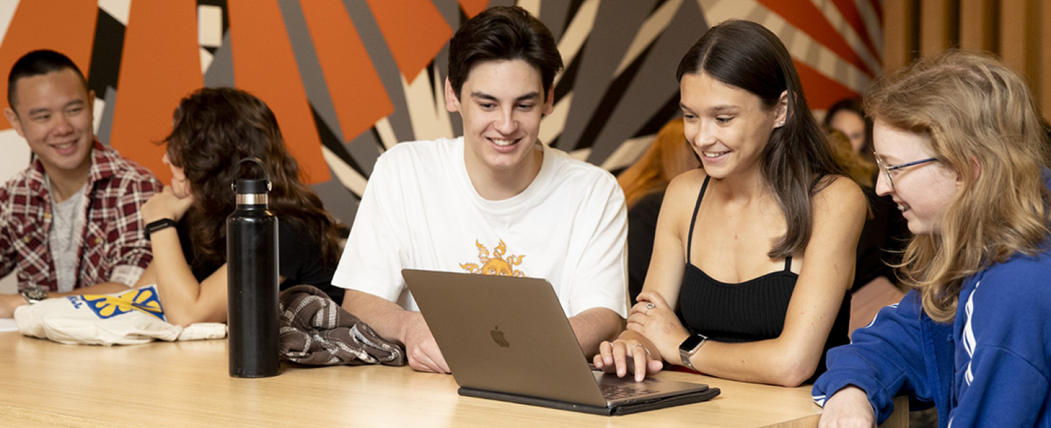 students in a teaching facility looking at a laptop and interacting